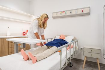 research participant attending to a manikin in a hospital bed