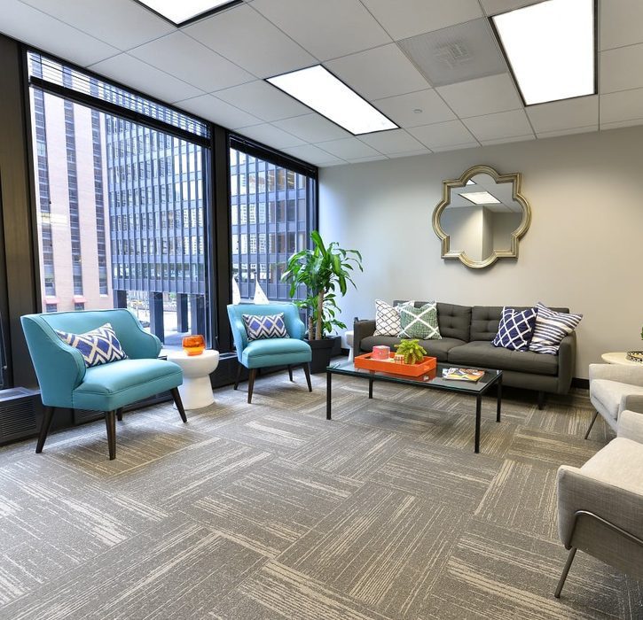 A large room with a couch and two blue chairs